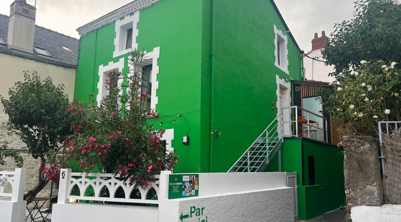 Een groen gebouw met een witte hekken, een trap en een bloemenhaag.