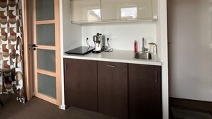 Una cocina pequeña con cafetera, pileta y alacenas.