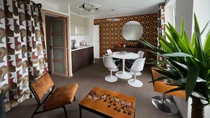 Una sala moderna con comedor, una planta grande y un muro estampado.