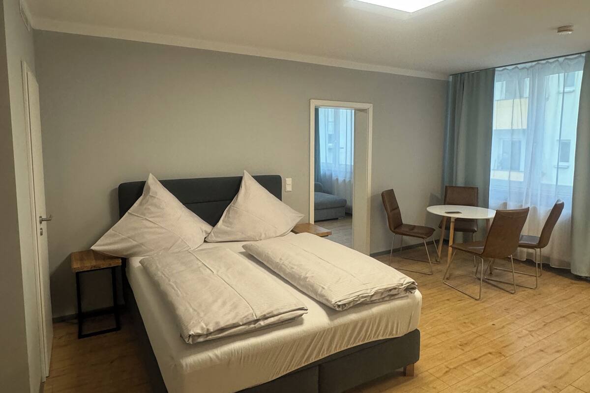 Une chambre à coucher moderne avec un lit, une petite table et une chaise.
