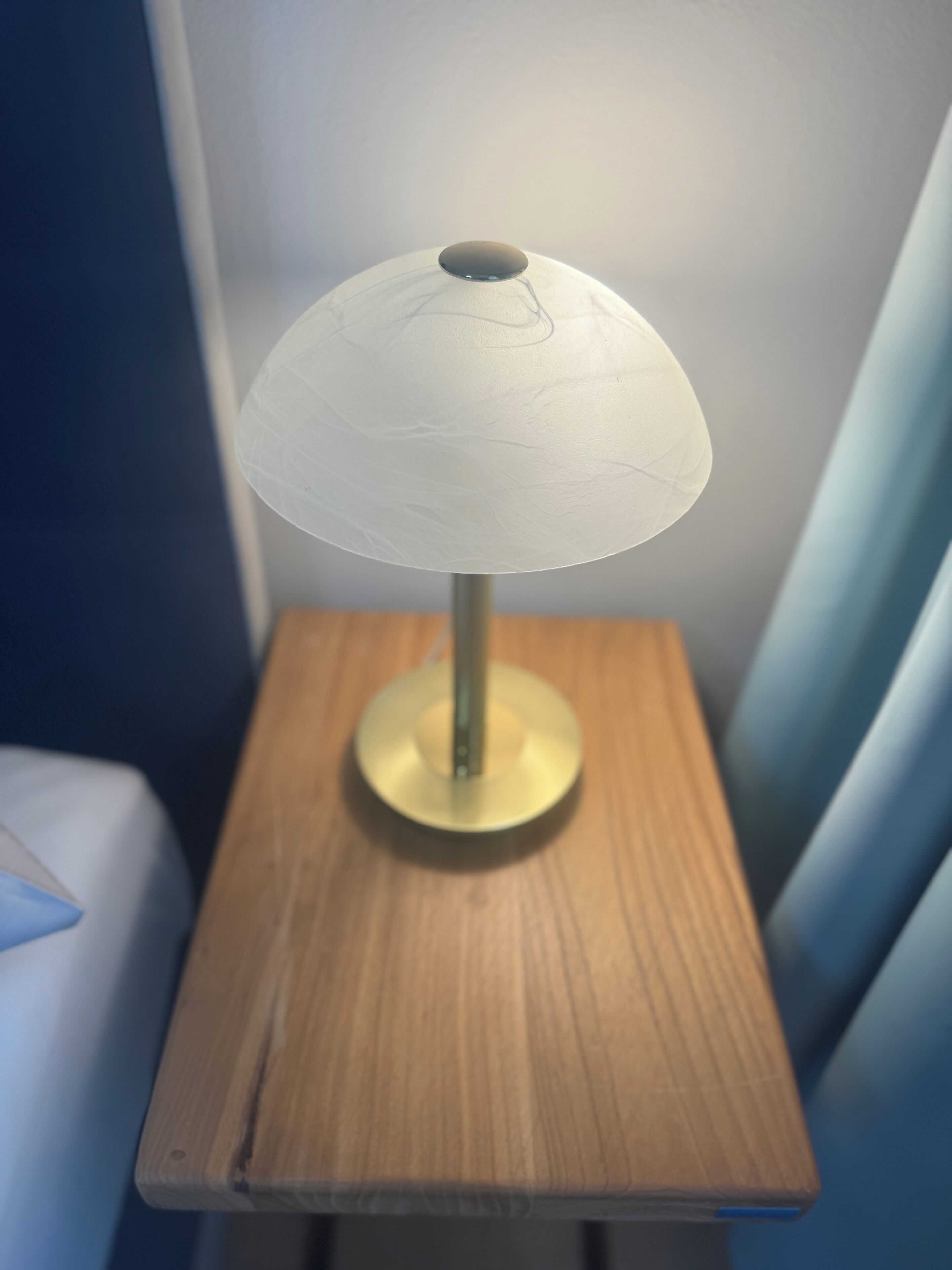 A table lamp with a white shade on a wooden nightstand.