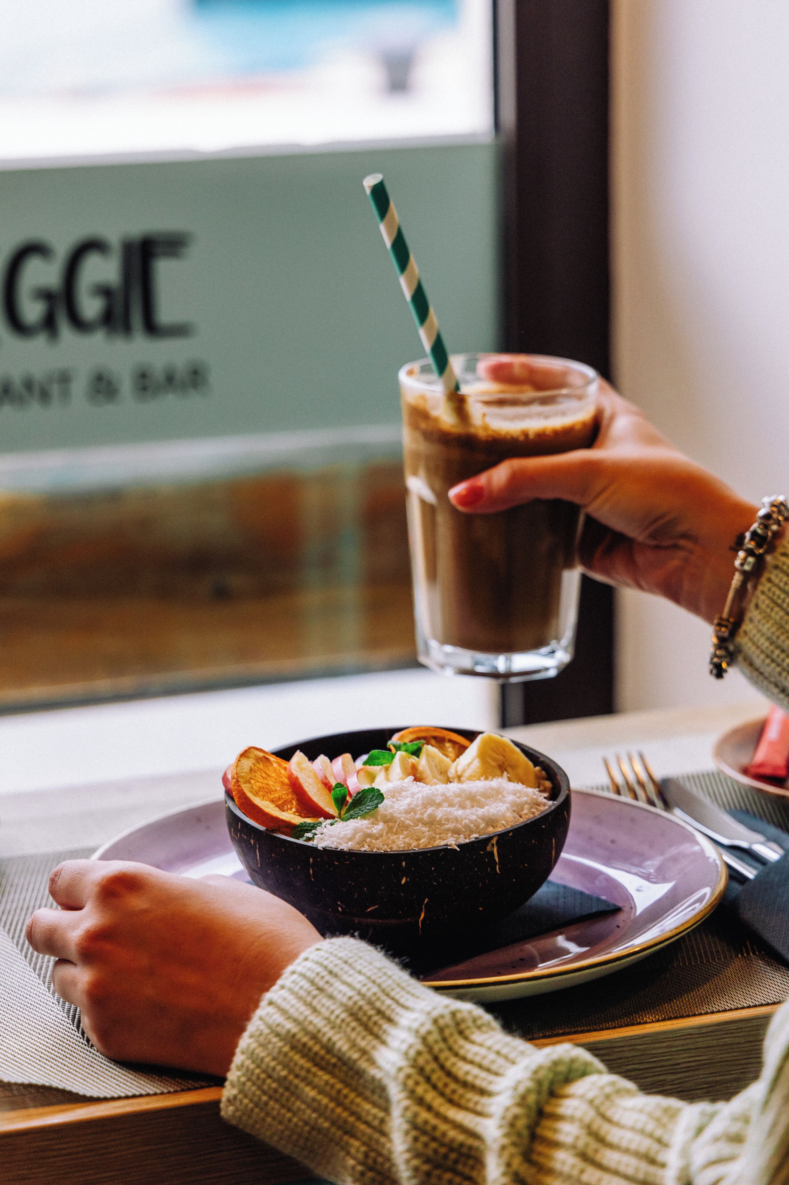 A bowl of food on a table with a drink in a glass.