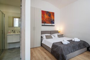 Um quarto com uma cama, mesa de cabeceira, espelho e um quadro na parede.
