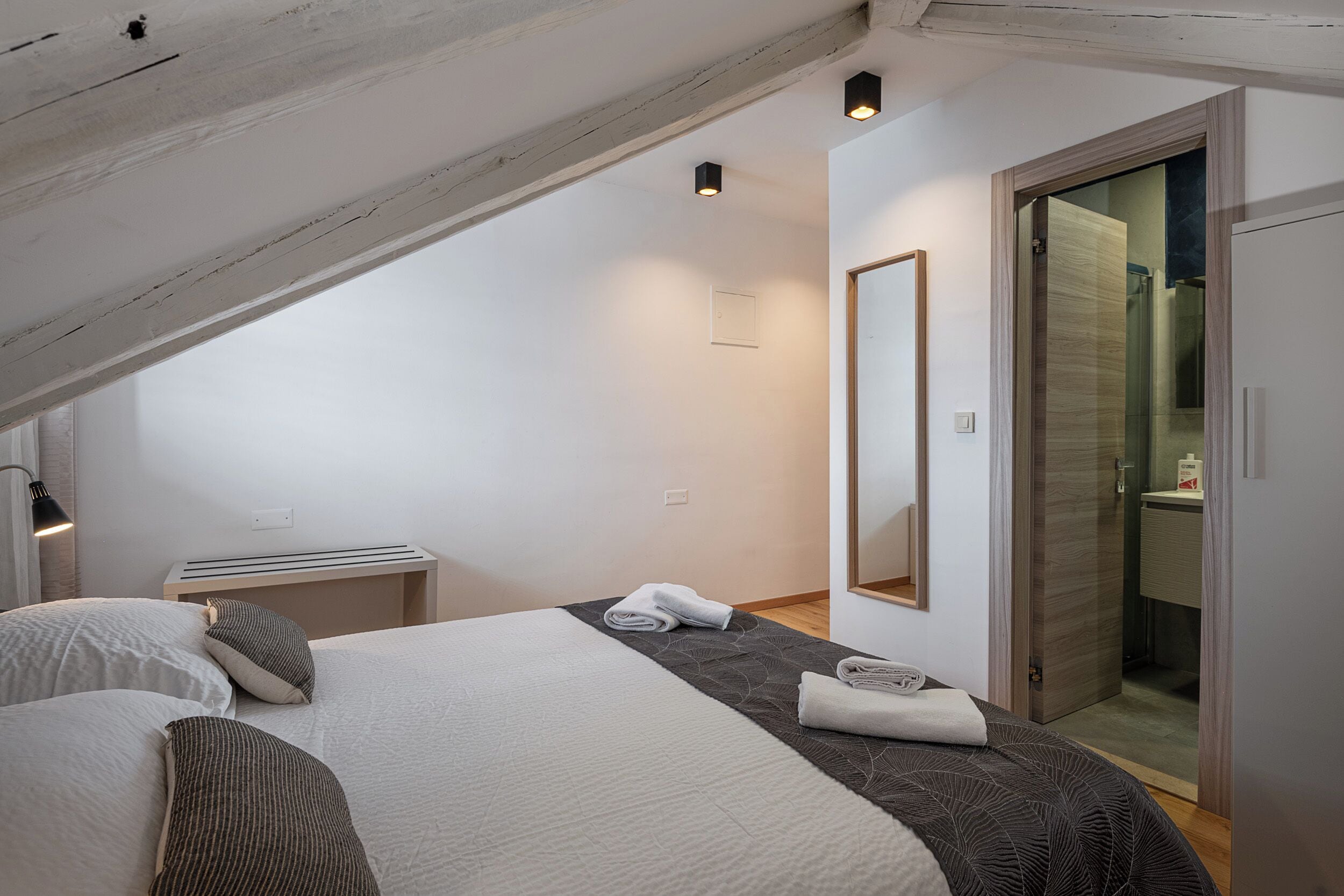 A bedroom with a bed, bedside table, and a mirror.