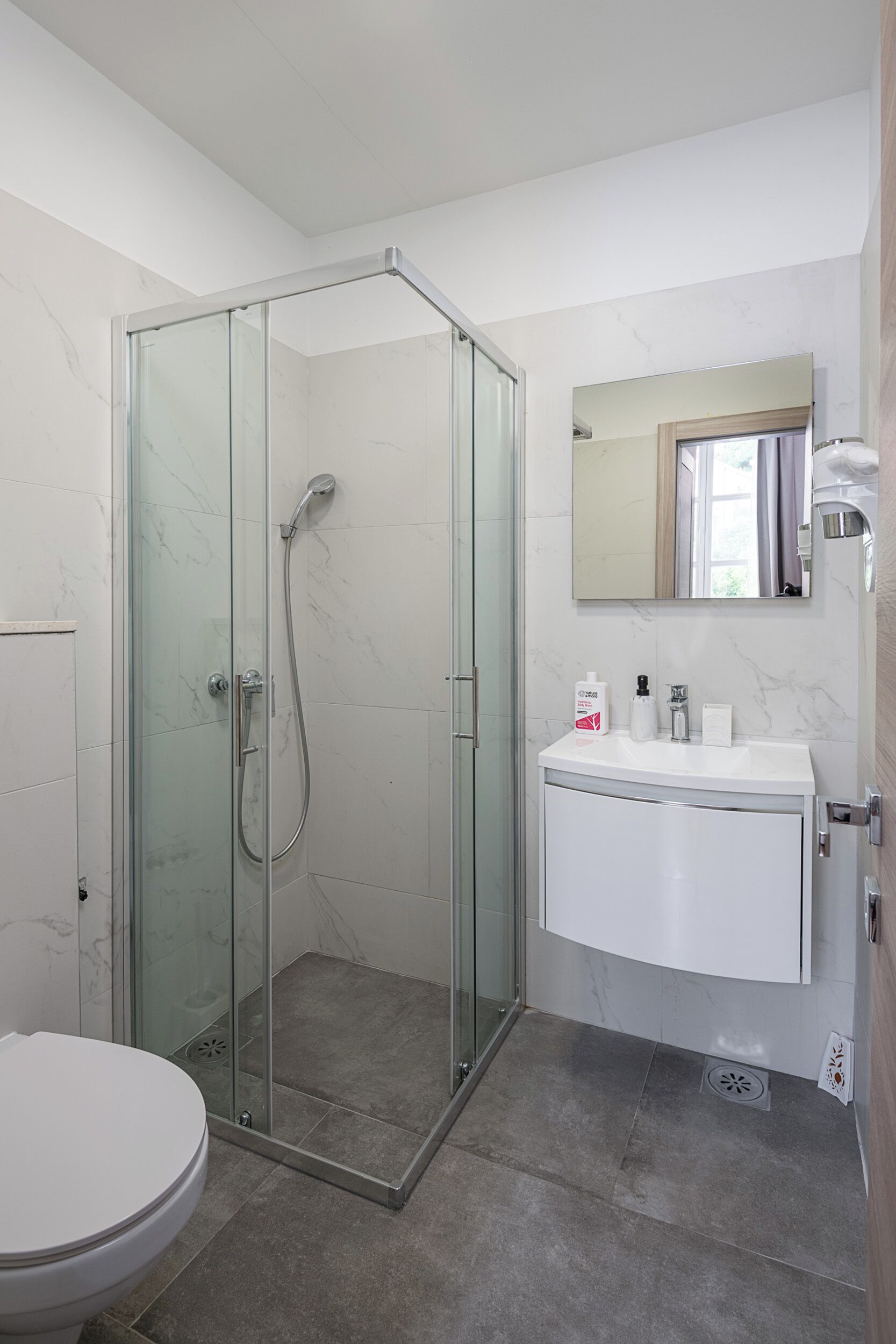 Une salle de bain moderne avec une douche à parois de verre, un lavabo blanc et des toilettes.