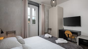 A hotel room with a bed, a desk, a chair, a television, and a view through a door.