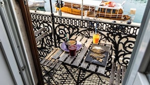 Uma varanda com uma mesa posta para dois, uma bebida e um lanche.