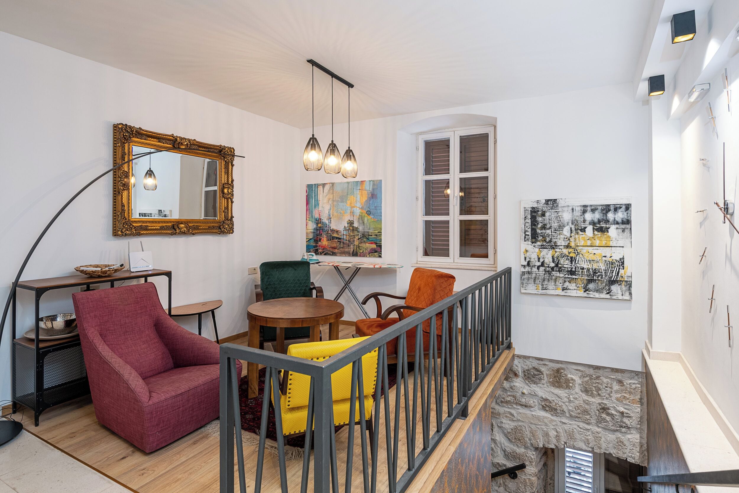 Een moderne woonkamer met een trap, een eethoek en kunstwerken aan de muren.