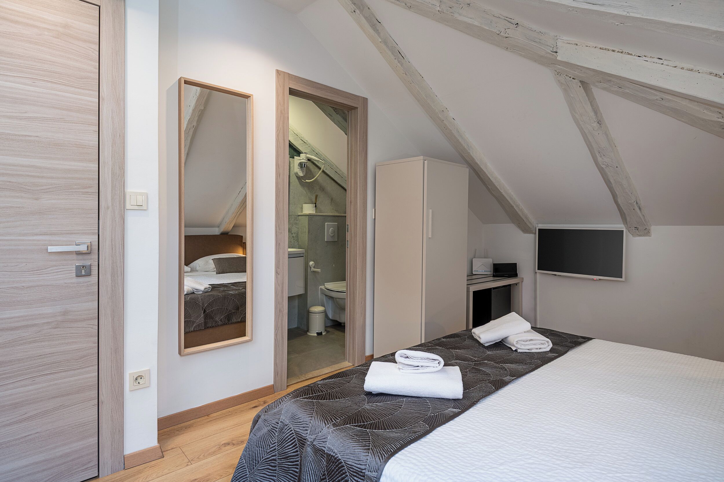 Une chambre à coucher avec un lit, une armoire, un miroir et un téléviseur.