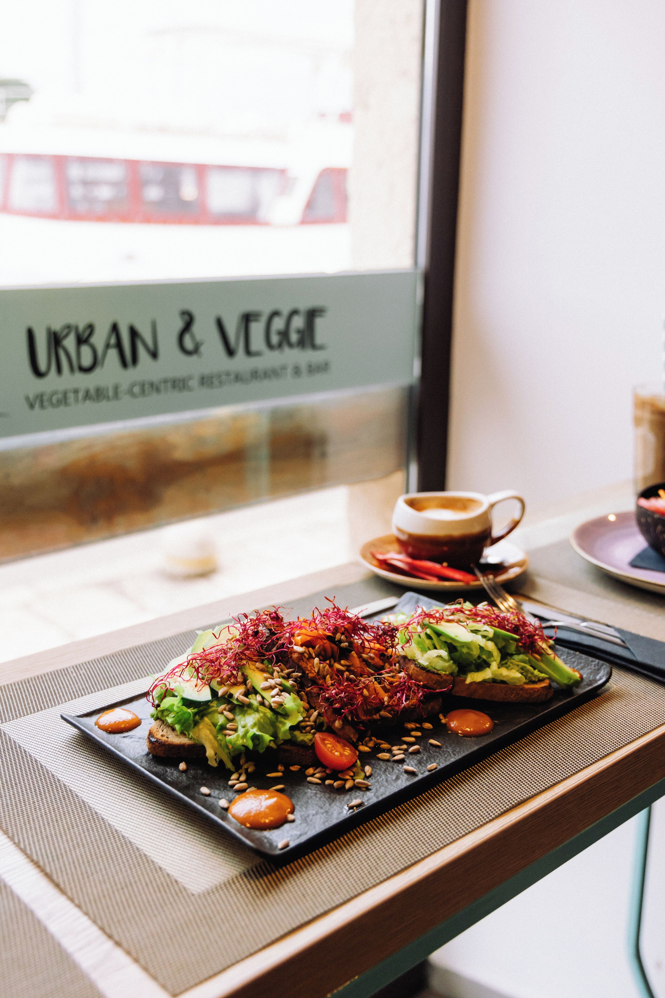 A restaurant with a menu board reading "URBAN & VEGGIE" and a plate of food on a table.