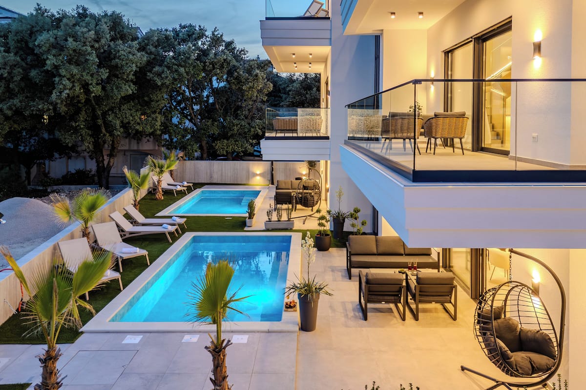 Un área de piscina moderna al aire libre con sillones de descanso y un comedor.