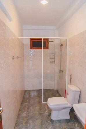 Compact bathroom with a shower enclosure, toilet, and patterned tile floor.
