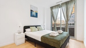Une chambre à coucher moderne avec un lit, une table de chevet, un tableau et une vue par la fenêtre.