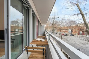 Un balcón con una mesa y sillas de madera, un libro y una taza.