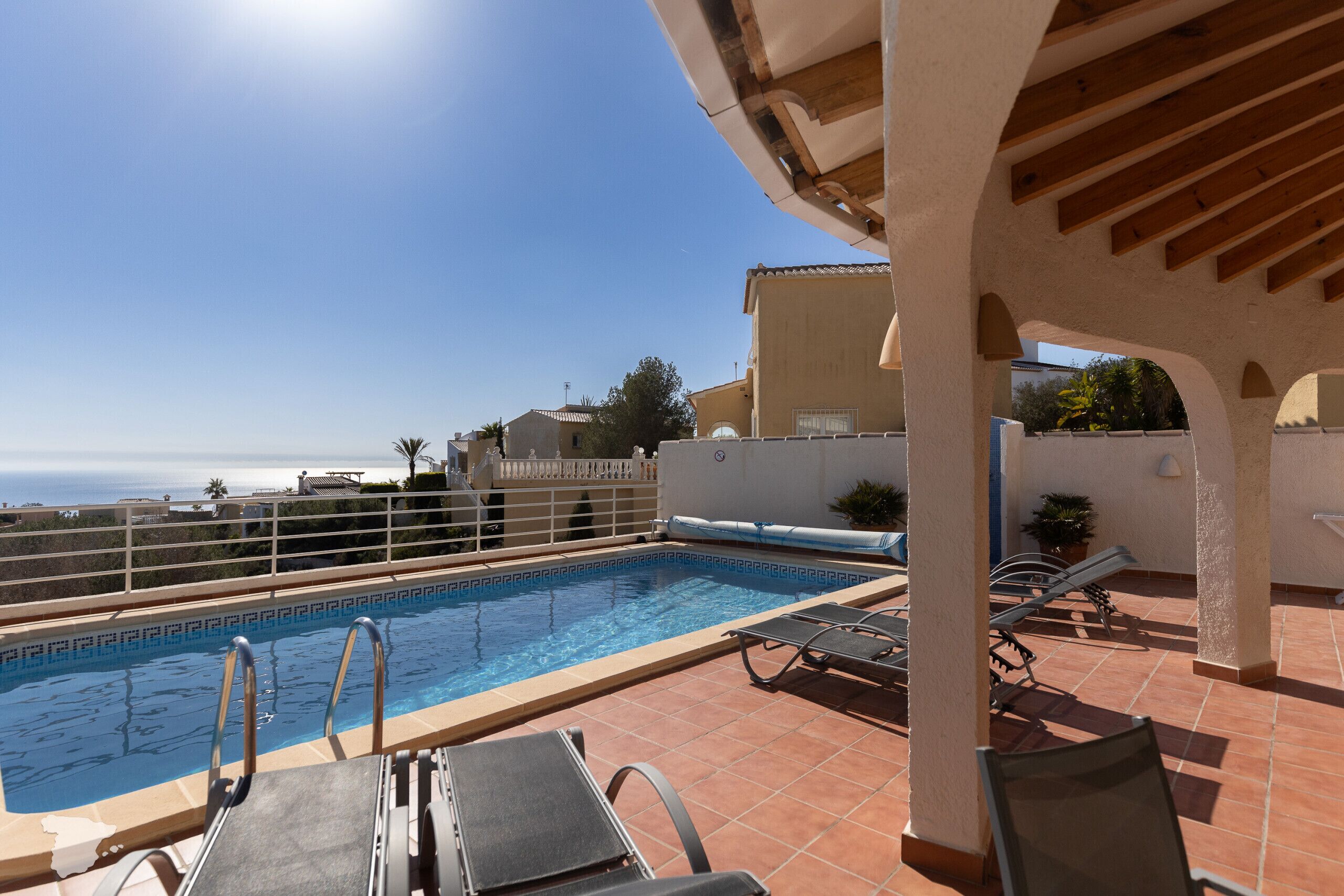 A rooftop pool with clear blue water, surrounded by lounge chairs and a pergola.