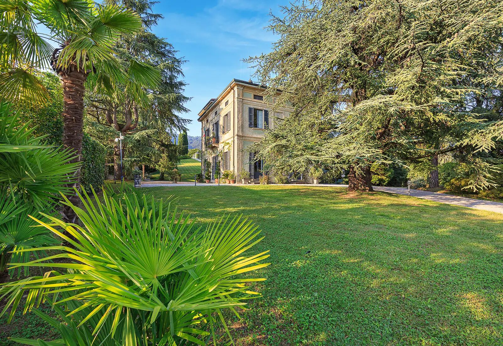 Un jardín bien cuidado con diversos árboles y un edificio de estilo arquitectónico clásico.