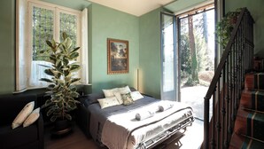 Un dormitorio con cama, una planta en maceta, una ventana y una escalera.