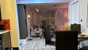 A modern living room with a sofa, coffee table, and chairs, a dining area with a table and chairs, and a kitchen area with a microwave.