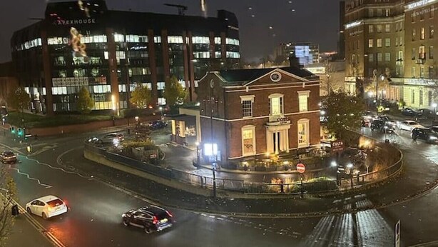 A roundabout with a historic building in the center, surrounded by modern buildings.