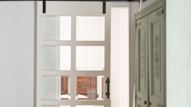 Une pièce dotée d’une grande fenêtre, d’une porte en bois et d’un meuble vert.