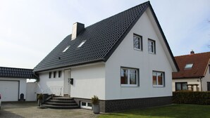A two-story house with a sloped roof, a front entrance with steps, and a paved driveway.