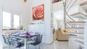 A modern kitchen with a dining area, a staircase, and a large window. - Apartment Aqua-Juric (Crikvenica)
