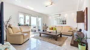 A modern living room with two beige sofas, a coffee table, and a large window. - Apartment Aqua-Juric (Crikvenica)