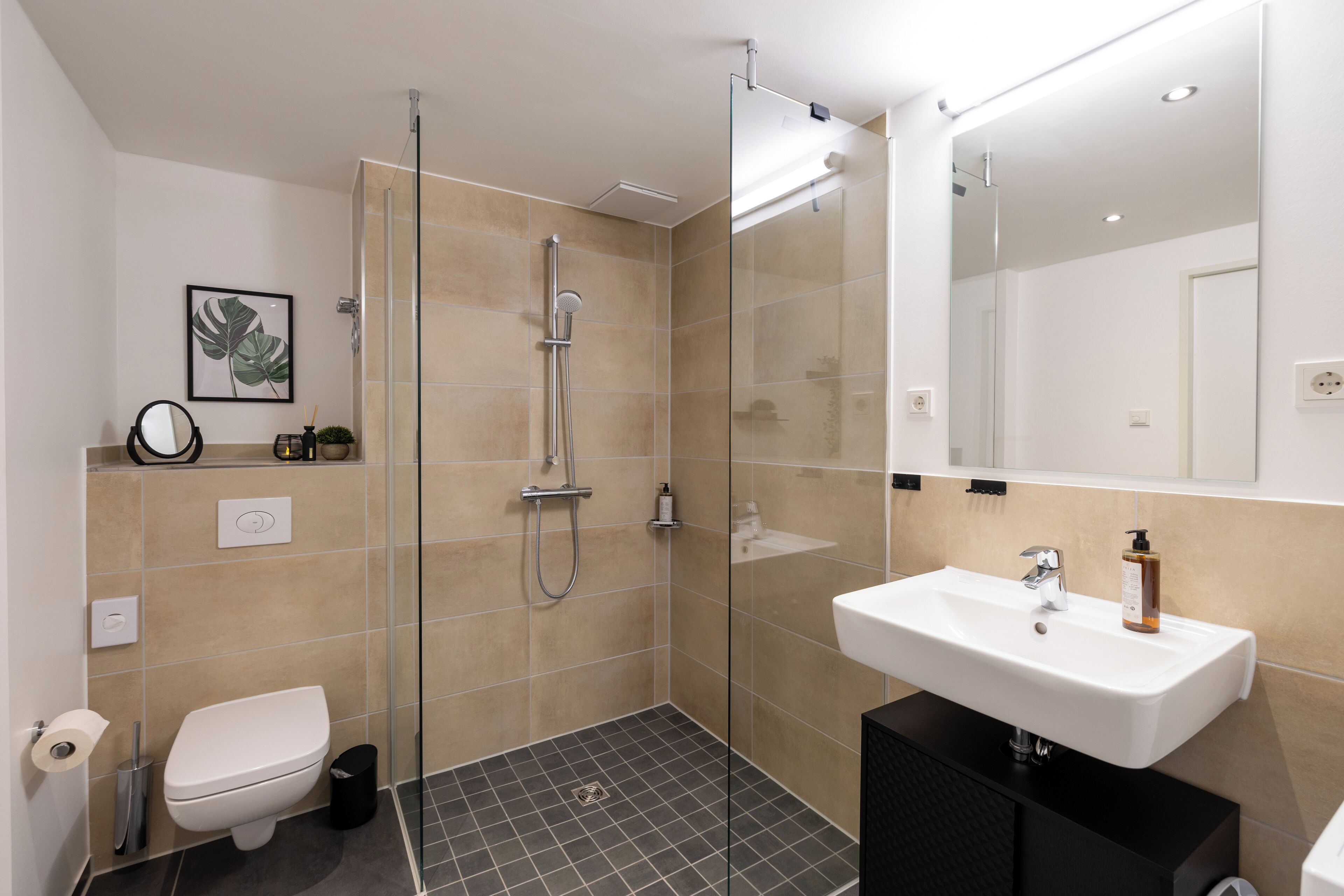Een moderne badkamer met een douchecabine van glas, een wit wastafelmeubel en een toilet.