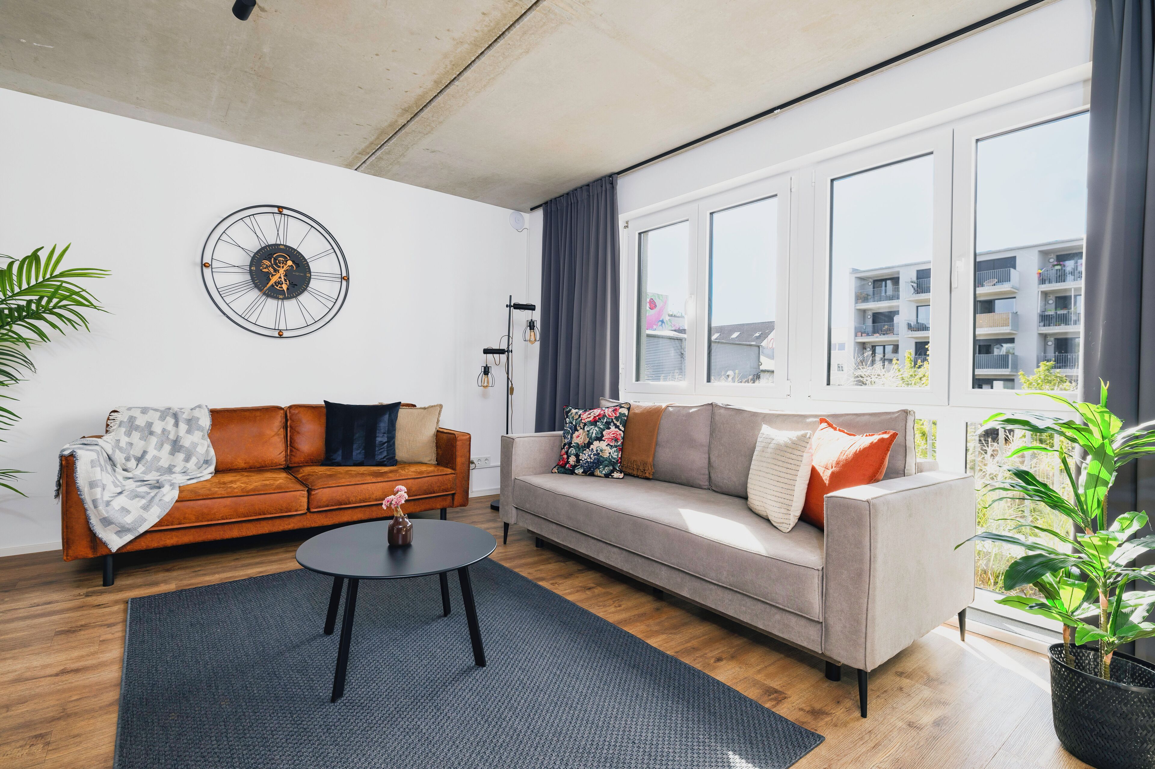 A modern living room with a sofa, coffee table, and a decorative clock on the wall.