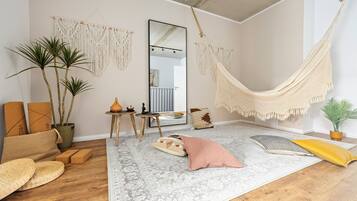 Ein Zimmer mit einer Hängematte, Wandbehängen aus Makramee, einem großen Spiegel und einem gemusterten Teppich.