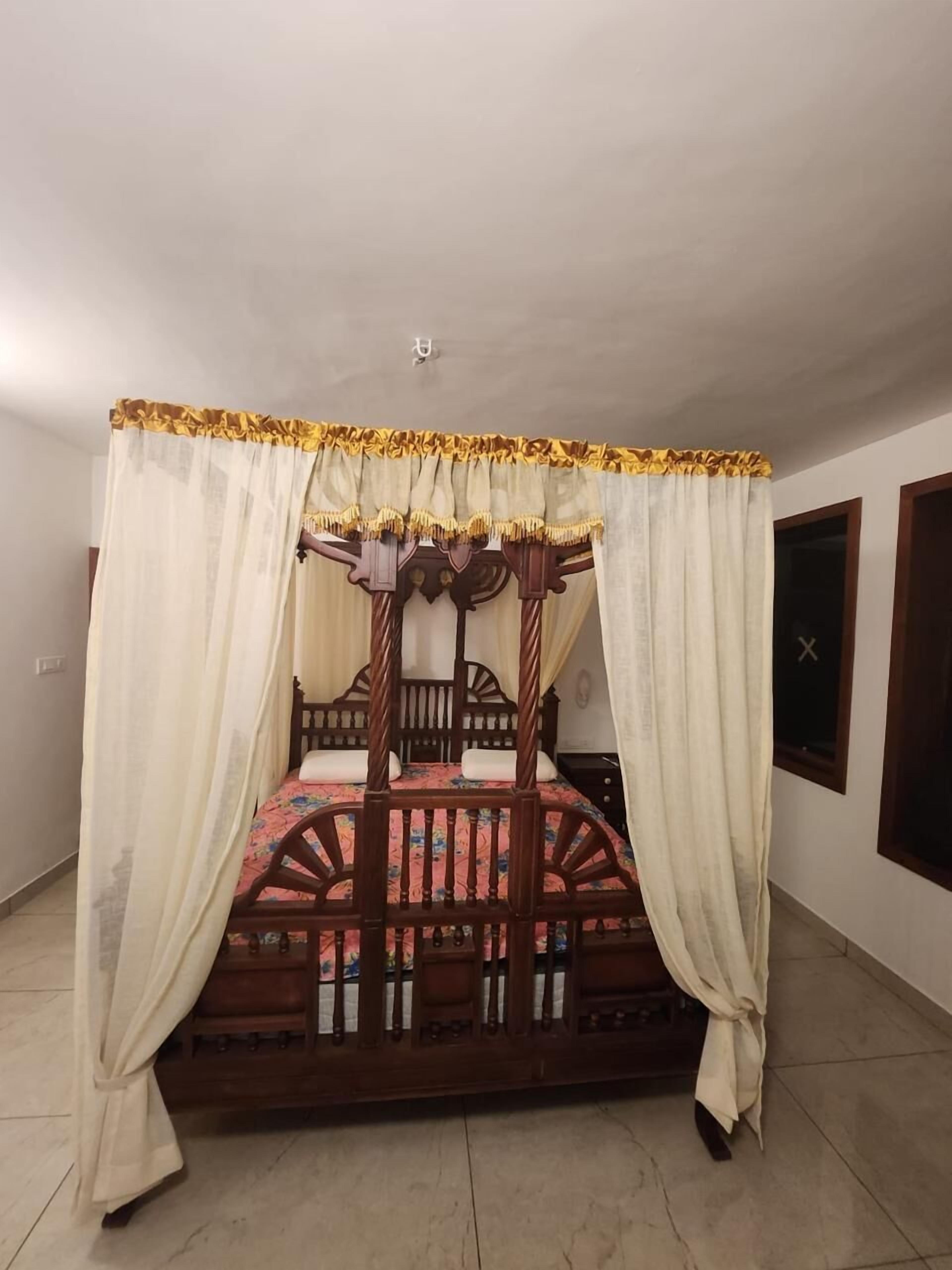 A four-poster bed with a canopy, wooden frame, and floral bedspread.