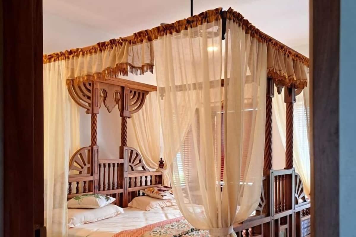 A four-poster canopy bed with a wooden frame and sheer curtains.
