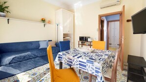 A compact living space with a sofa, a dining table, and a TV. - Lovely and typical apartment in the center of Sorrento (Campania)