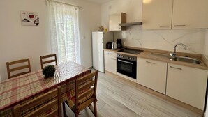Una cocina compacta con zona de comedor, que incluye una mesa con sillas, un refrigerador, una estufa y un lavaplatos.