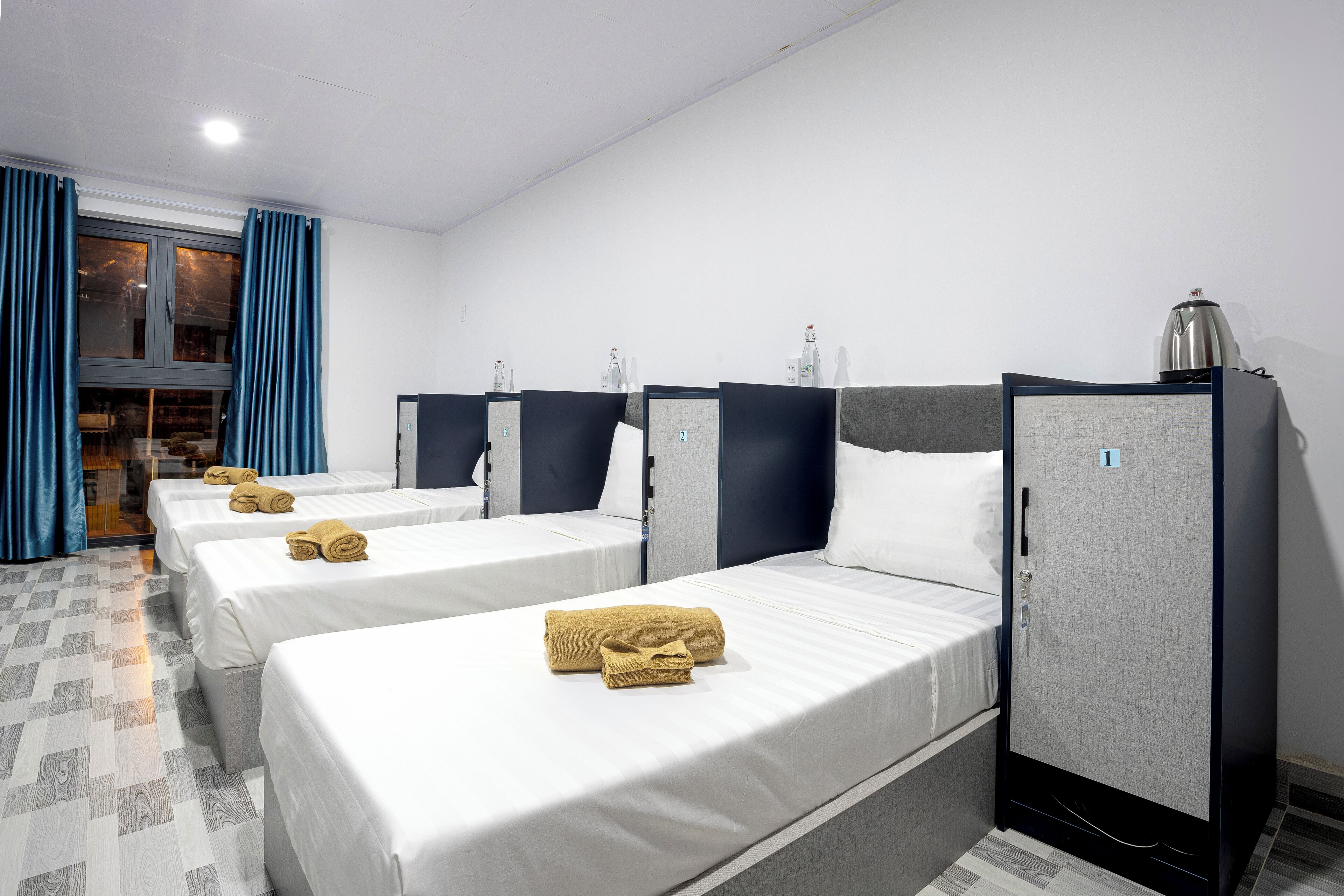 Une chambre d’hôtel avec deux lits, chacun agrémenté d’une serviette roulée, d’une armoire et d’une fenêtre avec des rideaux.