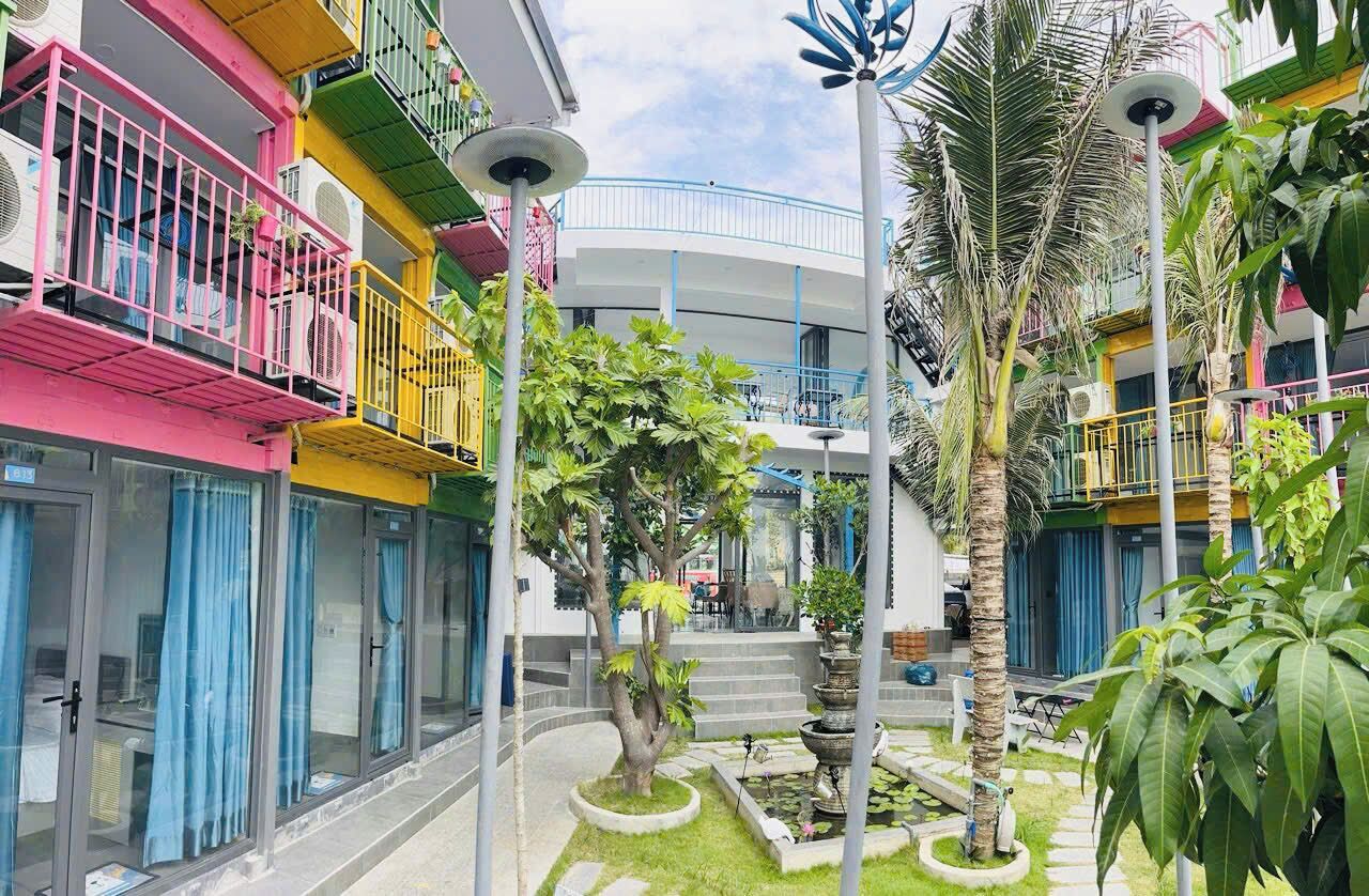 A multi-story building with balconies, a central courtyard with palm trees, and a water feature.