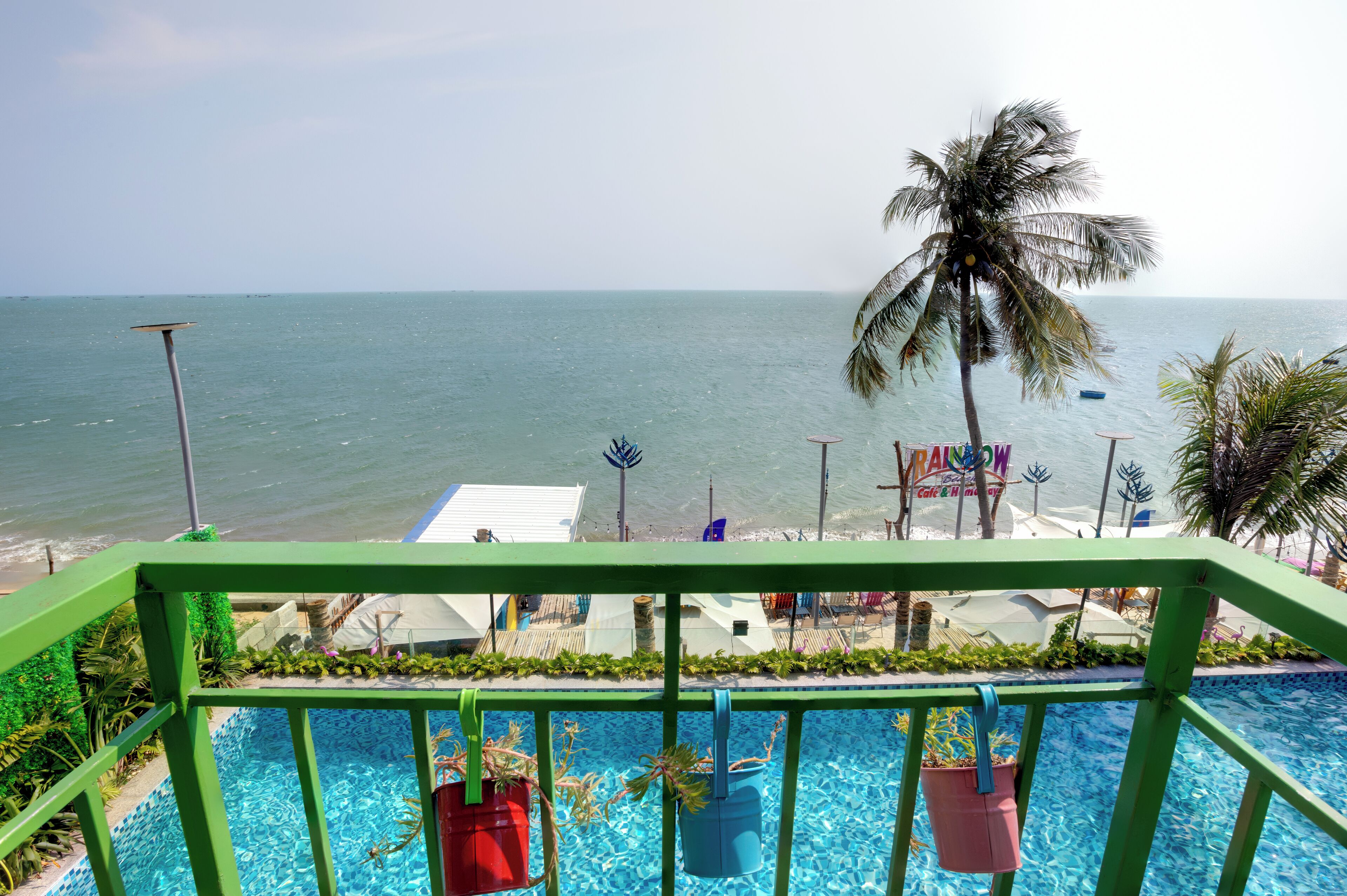 A pool area with a view of the ocean, surrounded by greenery and palm trees.