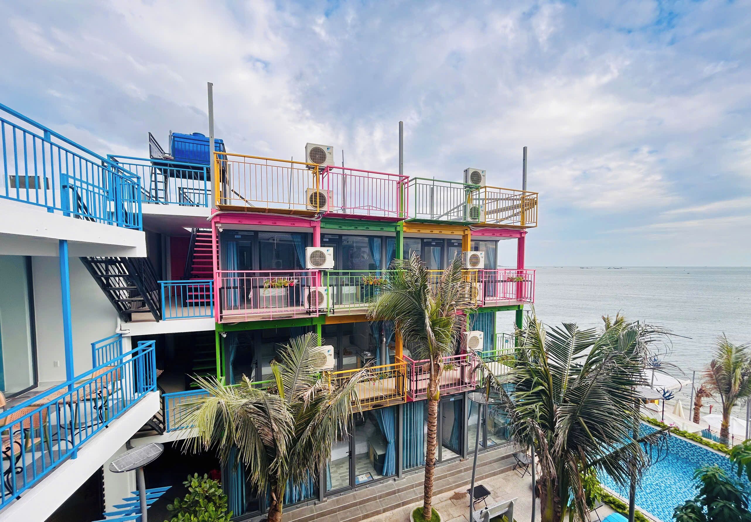 Un hotel de varios pisos con balcones, unidades de aire acondicionado y una zona de piscina.