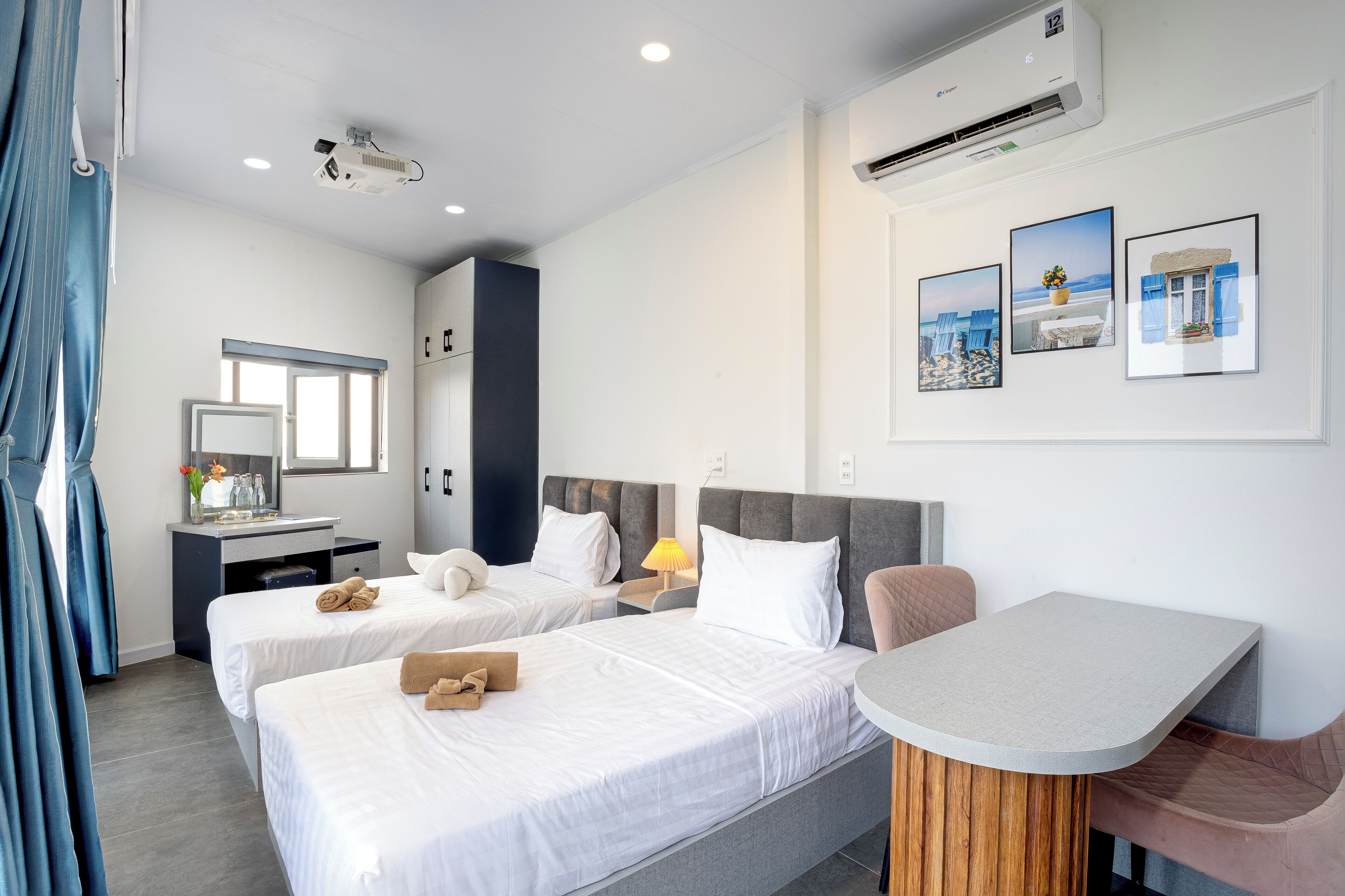 Habitación de hotel con dos camas, un escritorio, una silla y una mesita.