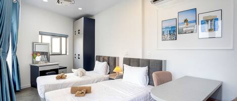 A hotel room with two beds, a desk, a chair, and a small table.