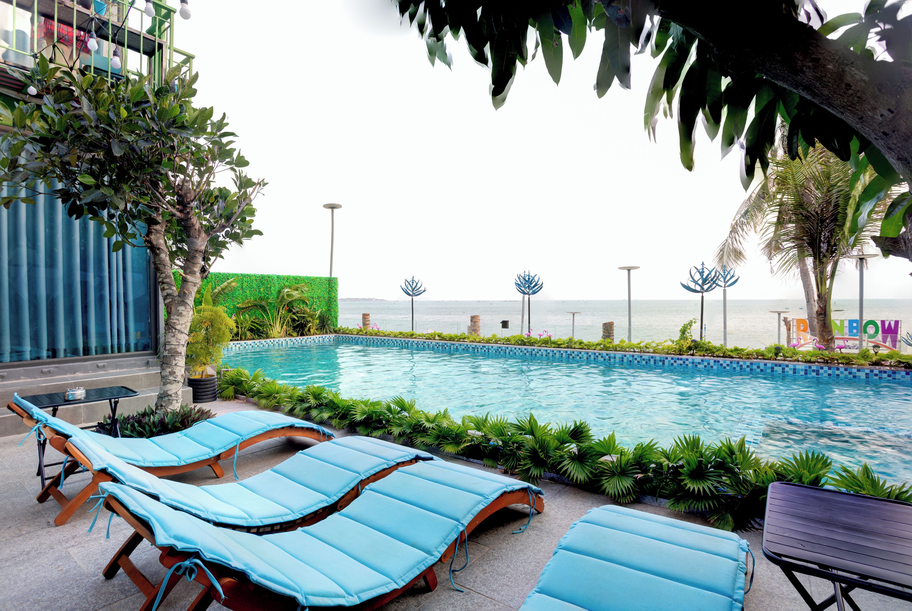 A poolside area with lounge chairs and a view of the sea.