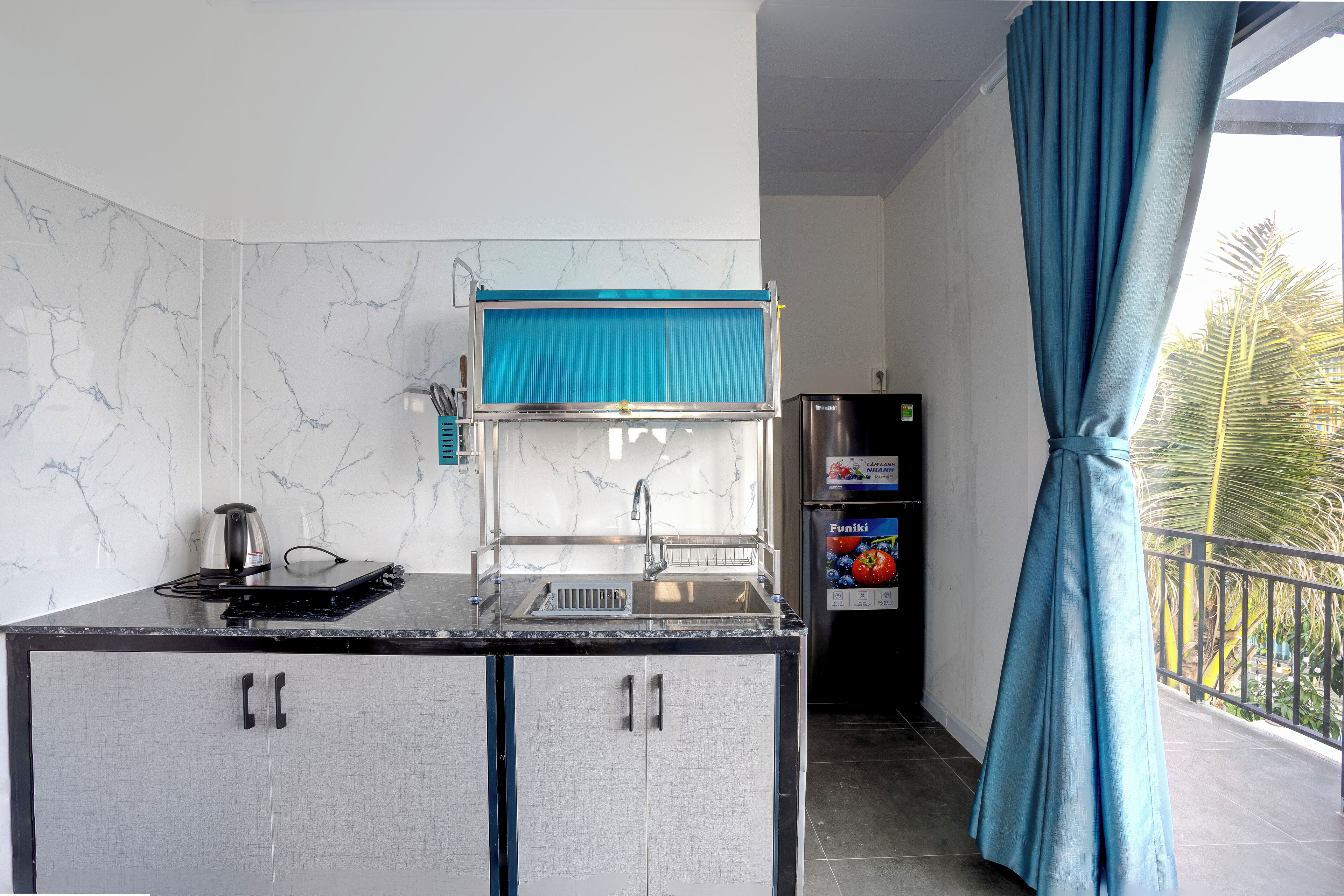 A compact kitchen with a built-in coffee maker, a sink, and a refrigerator.