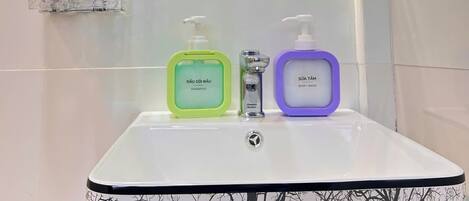 Un bagno con un lavandino bianco, uno specchio e tre articoli da toilette.