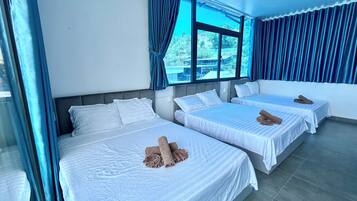 Una habitación de hotel con dos camas, un ventanal con cortinas y un ventilador de techo.