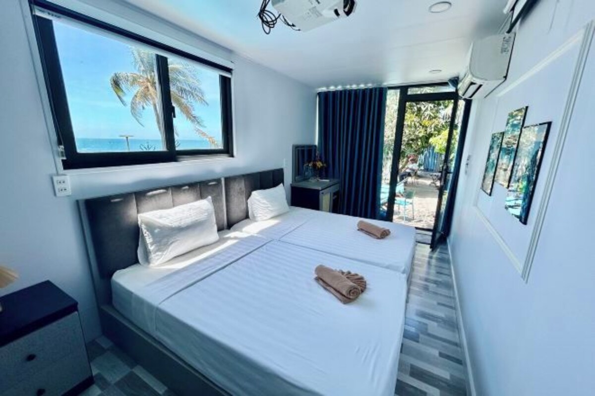 A hotel room with a large bed, a desk, a window with a view, and a balcony.