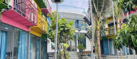 Um pátio com edifícios coloridos, uma fonte e palmeiras.