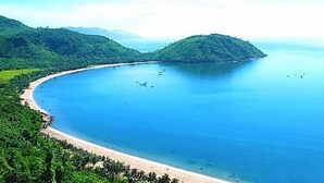 Un paisaje costero con una playa, una pequeña isla y un cielo despejado.