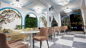 Una cafetería moderna con mesas redondas, sillas acolchadas y decoración mural.