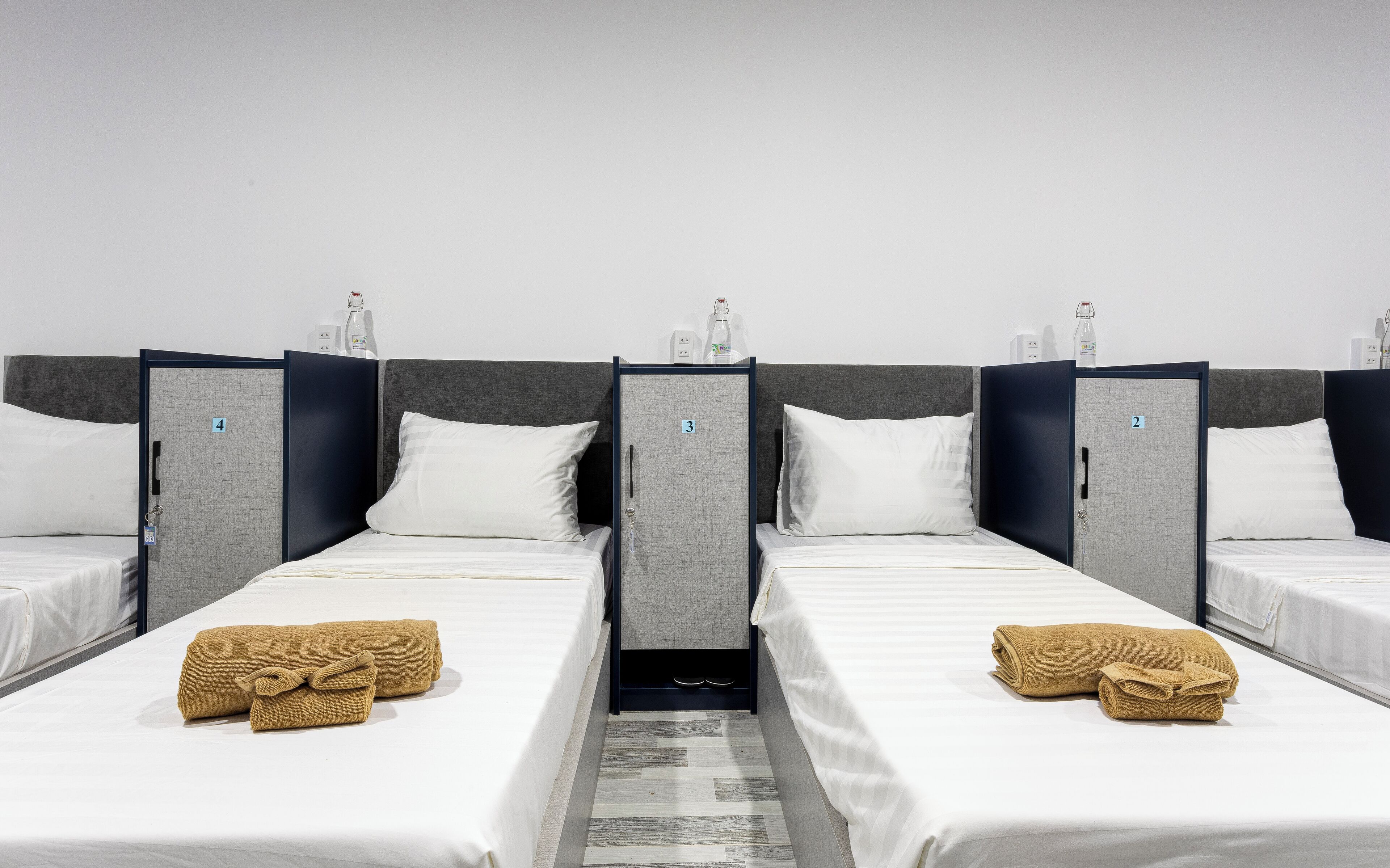Ein Hotelzimmer mit vier in einer Reihe stehenden Betten, jedes mit einer Nummer versehen.