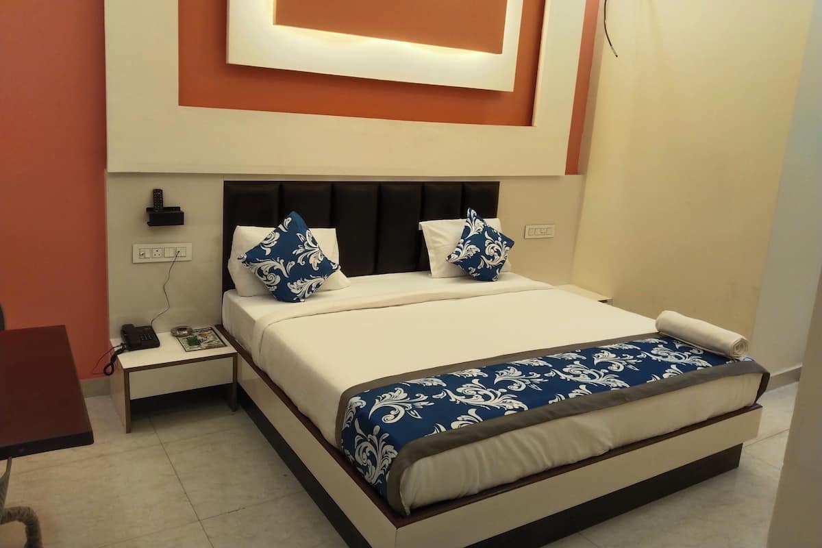 A neatly arranged bedroom with a bed, bedside tables, and a wall-mounted light fixture.